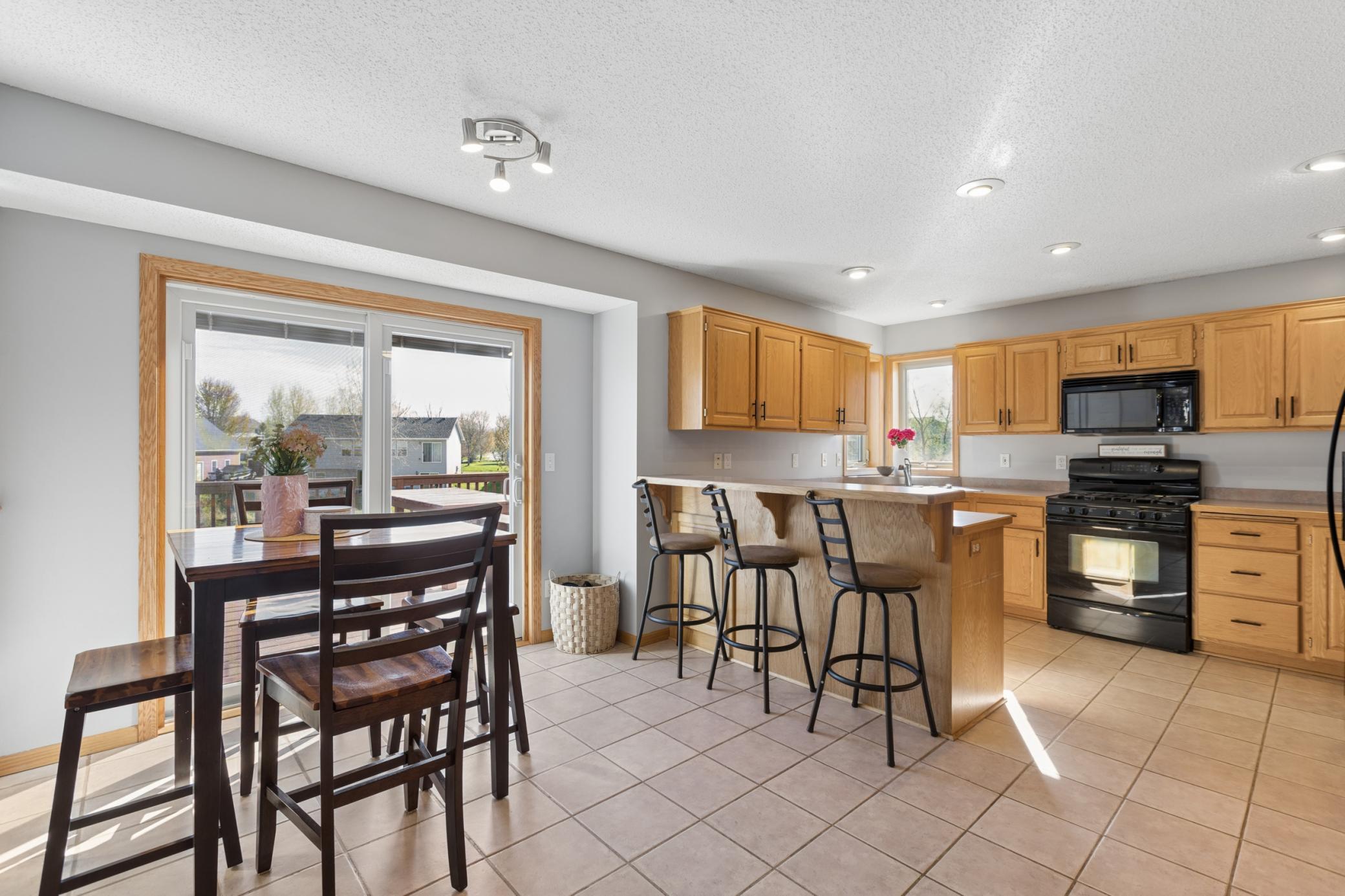 The kitchen/dining area offers beautiful ceramic tiled flooring, a breakfast bar area for extra counter seating, recessed lighting, neutral paint, and a large slider door that opens up to the wonderful deck and back yard!