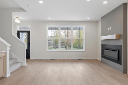 Sophisticated main level with durable SPC flooring, anchored by a statement fireplace with granite surround and wood mantle.