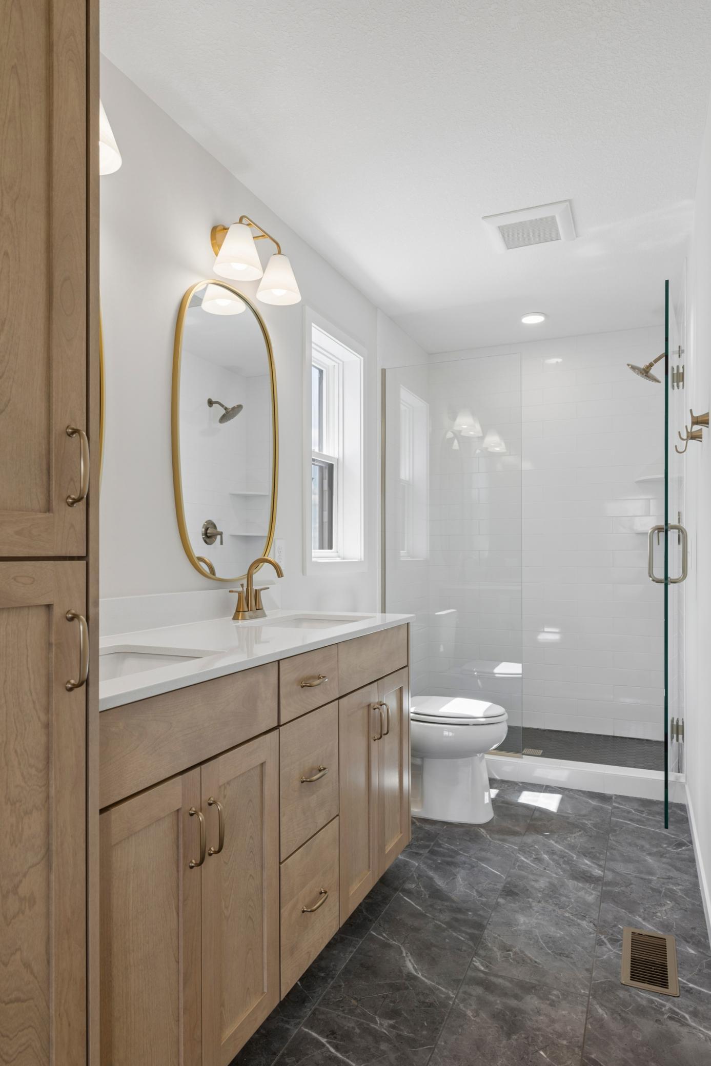 Luxurious primary suite is a tranquil retreat with spacious walk-in closet, ensuite bathroom, dual vanities, and ceramic tile shower and heavy glass door.