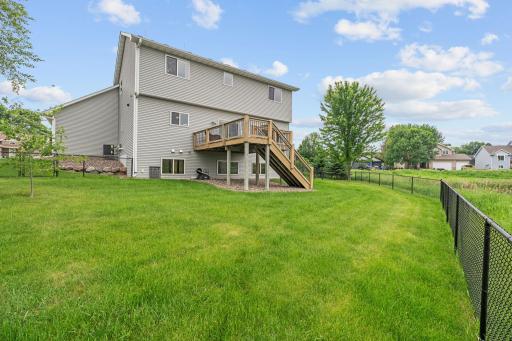 Large fenced in backyard with oversized deck and view of pond