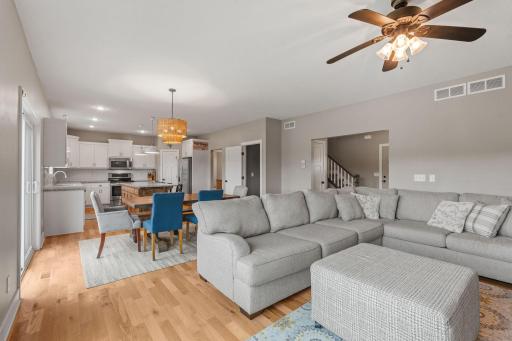 Living room, with view of stairway to upstairs in back right corner. Door to basement open in middle back of picture. Mudroom and entrance to garage between fridge and door to go downstairs.