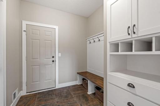 Mudroom with large closet on left and storage, bench seat with hooks on right