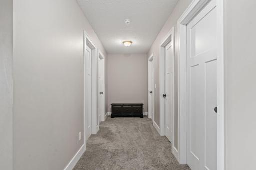 Upstairs hallway with doors to three bedrooms, guest bathroom, and laundry room