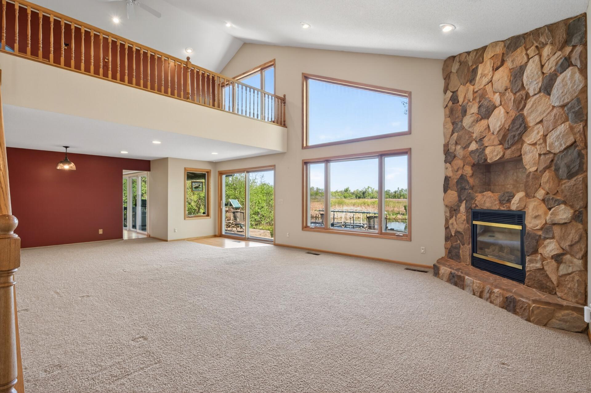 Great room features a floor to ceiling stone fireplace focal point, lofted area and expansive views of the lake!