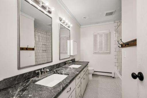 Full bathroom on the main level with a double vanity, tile floors and tile tub surround