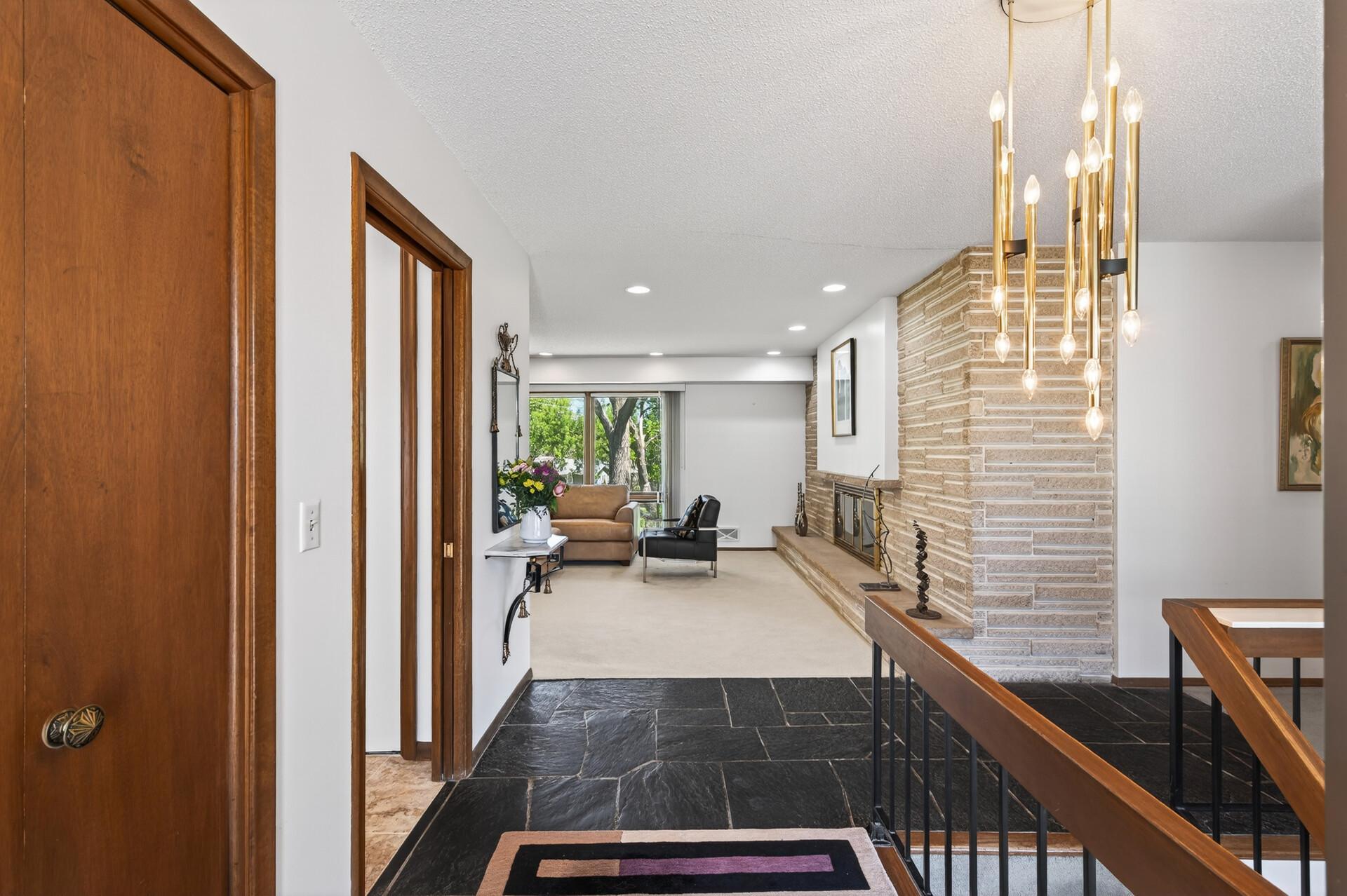 Mid Century slate foyer opens to the beveled stone wall in living room