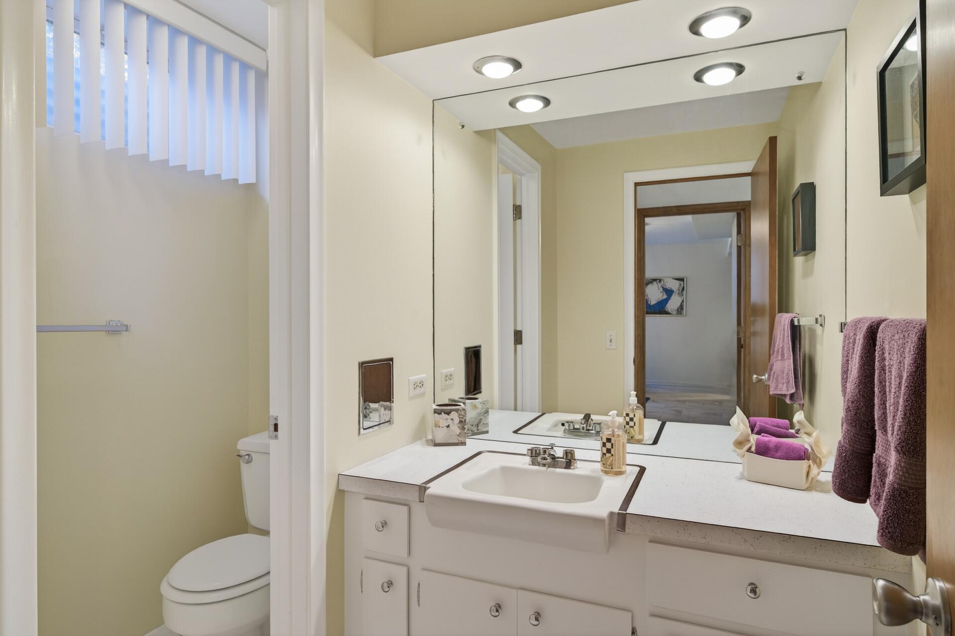 Lower level 3/4 bath has white marble flooring and a shower across from the commode