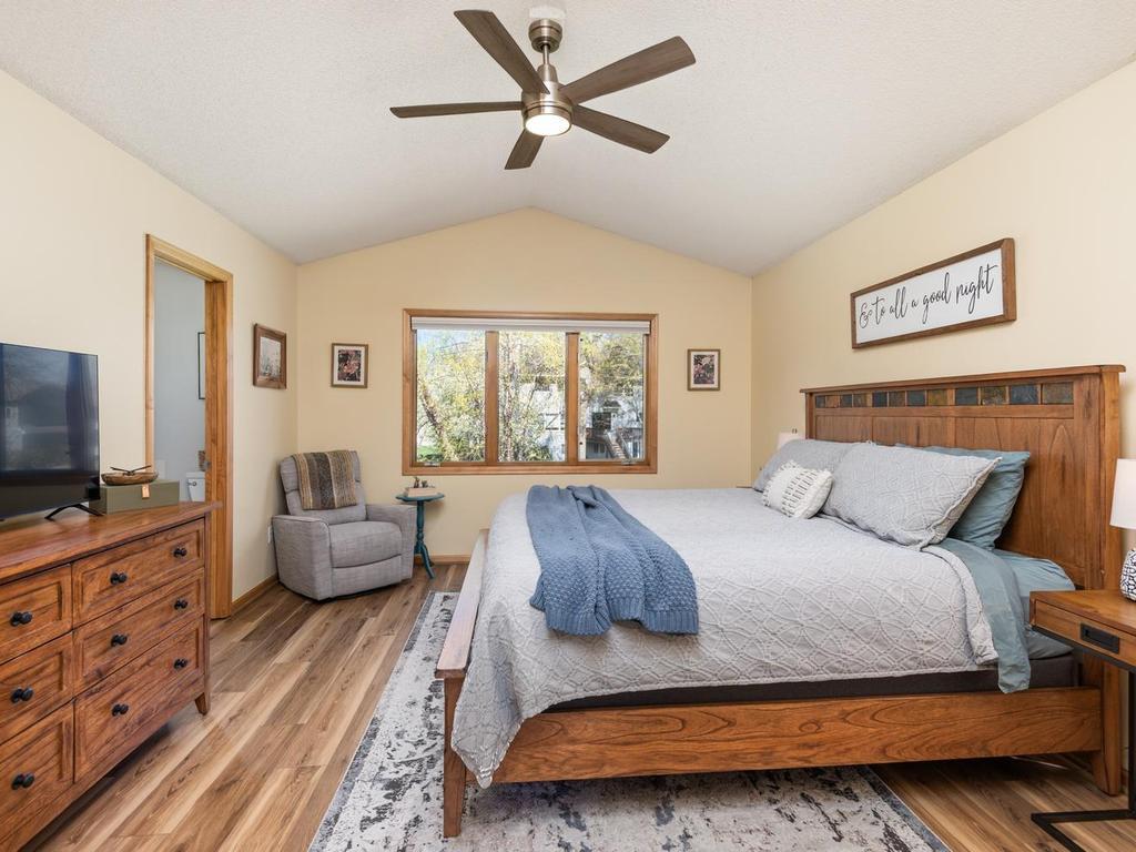 On the upper level, two French doors swing open to a spacious 15’5” x 12’6” primary bedroom with vaulted ceiling and new ceiling fan.