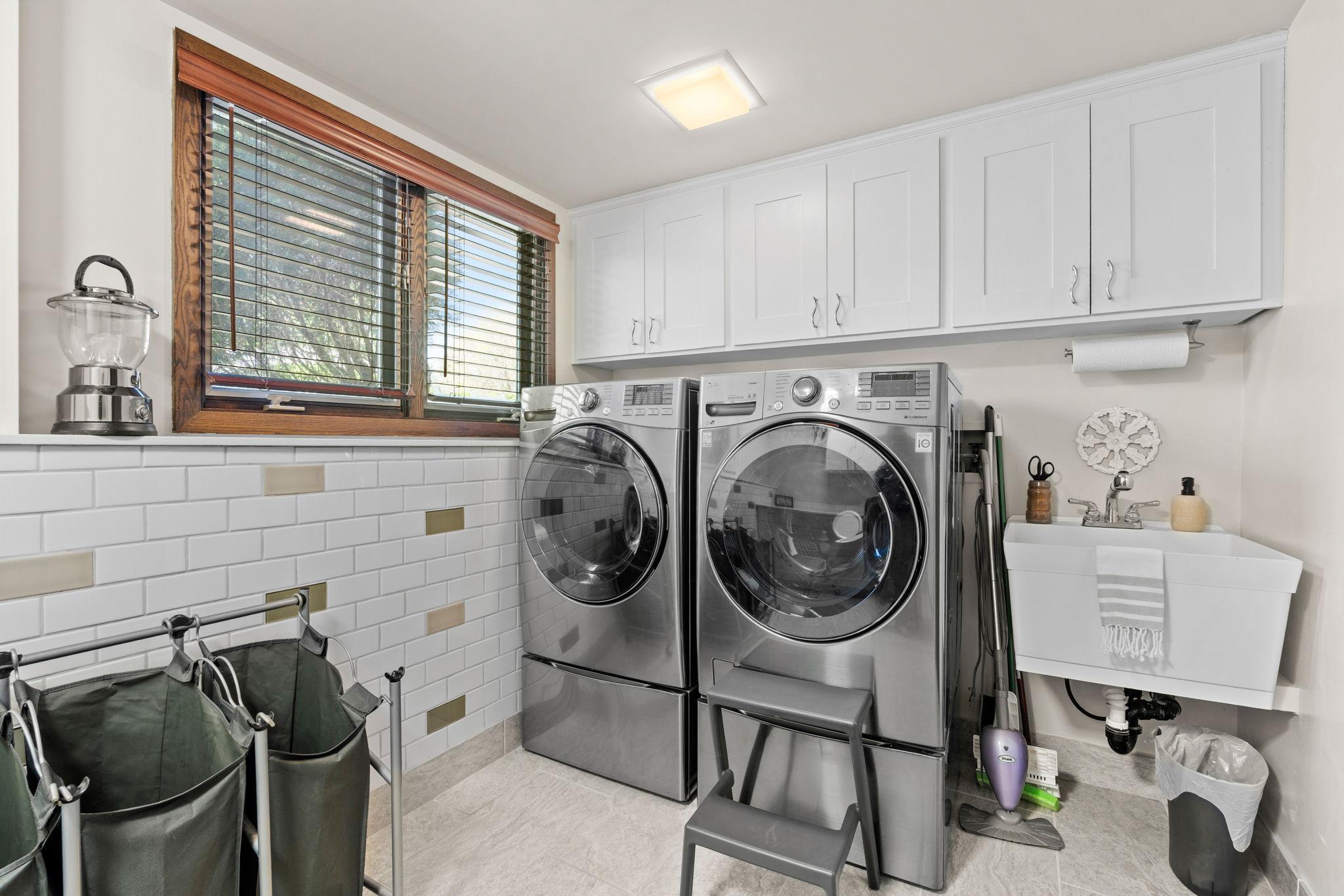 The laundry room! Spacious with updated washer/dryer, laundry sink and cabinet storage.