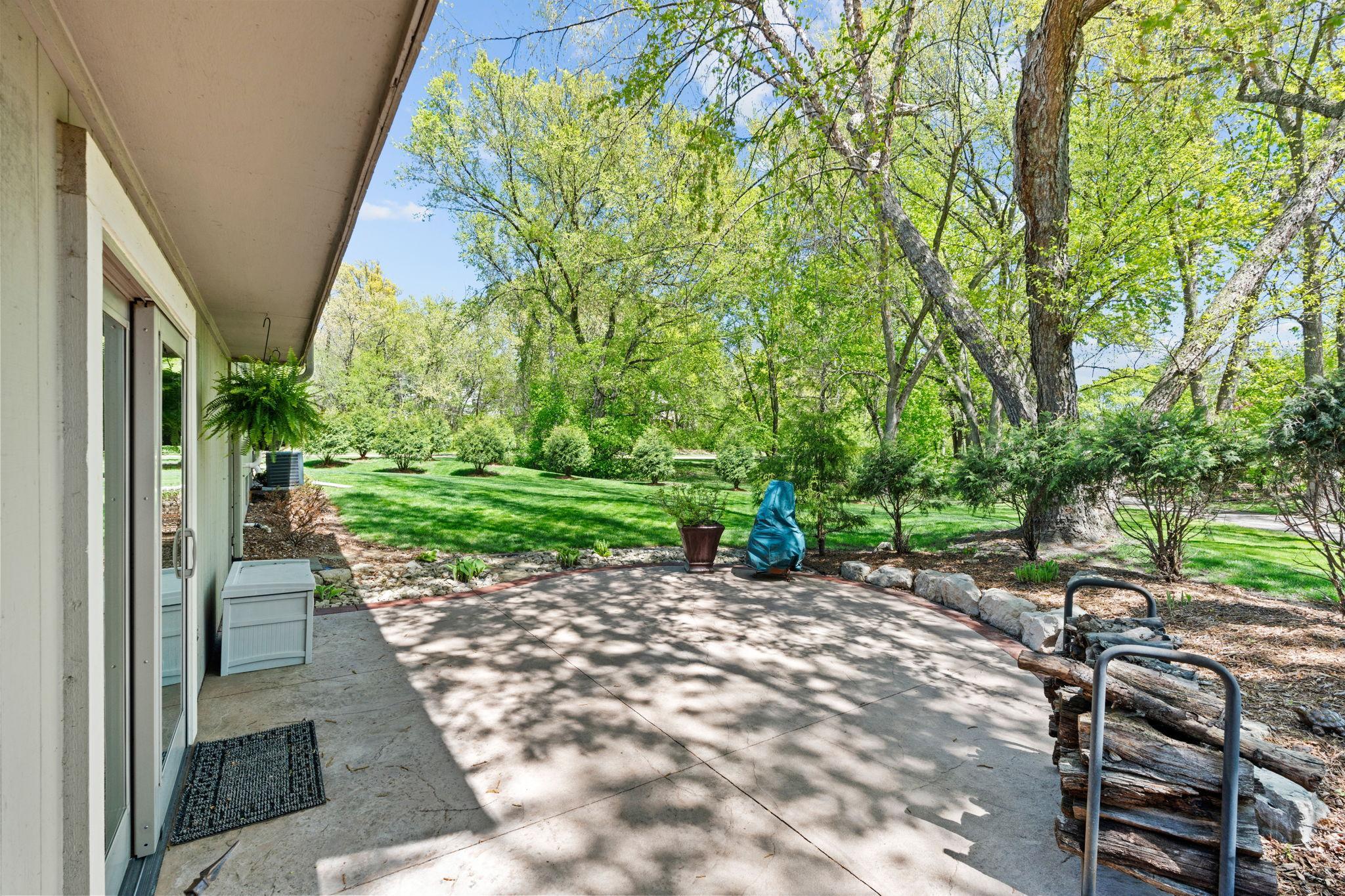 View of the backyard from the patio, enjoy mature trees dotted along the property & walking trail access right behind the home!