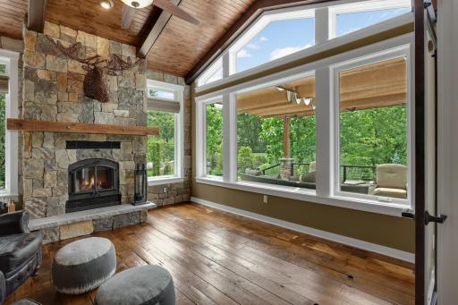 Walls of windows and a soaring wood-planked vaulted ceiling fill this stunning sunroom with natural light, while a beautiful wood-burning fireplace creates the perfect place to relax all year round.