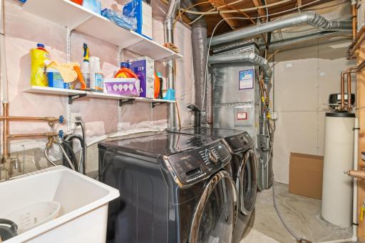Lower-level utility room with newer furnace, washer/dryer and utility sink!