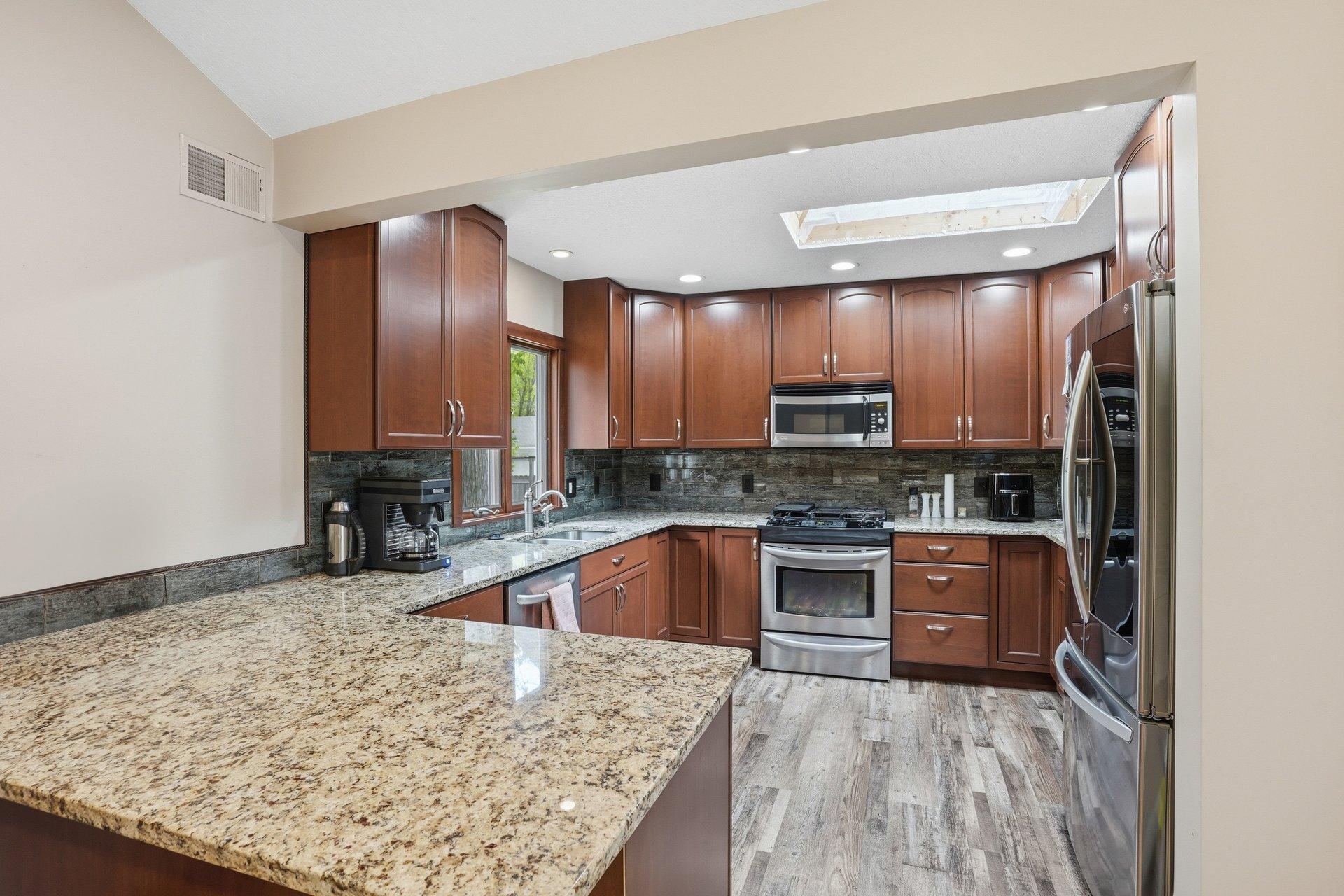 Beautifully updated kitchen featuring rich dark cabinetry, granite countertops, stainless steel appliances, and timeless finishes that blend style and functionality perfectly.