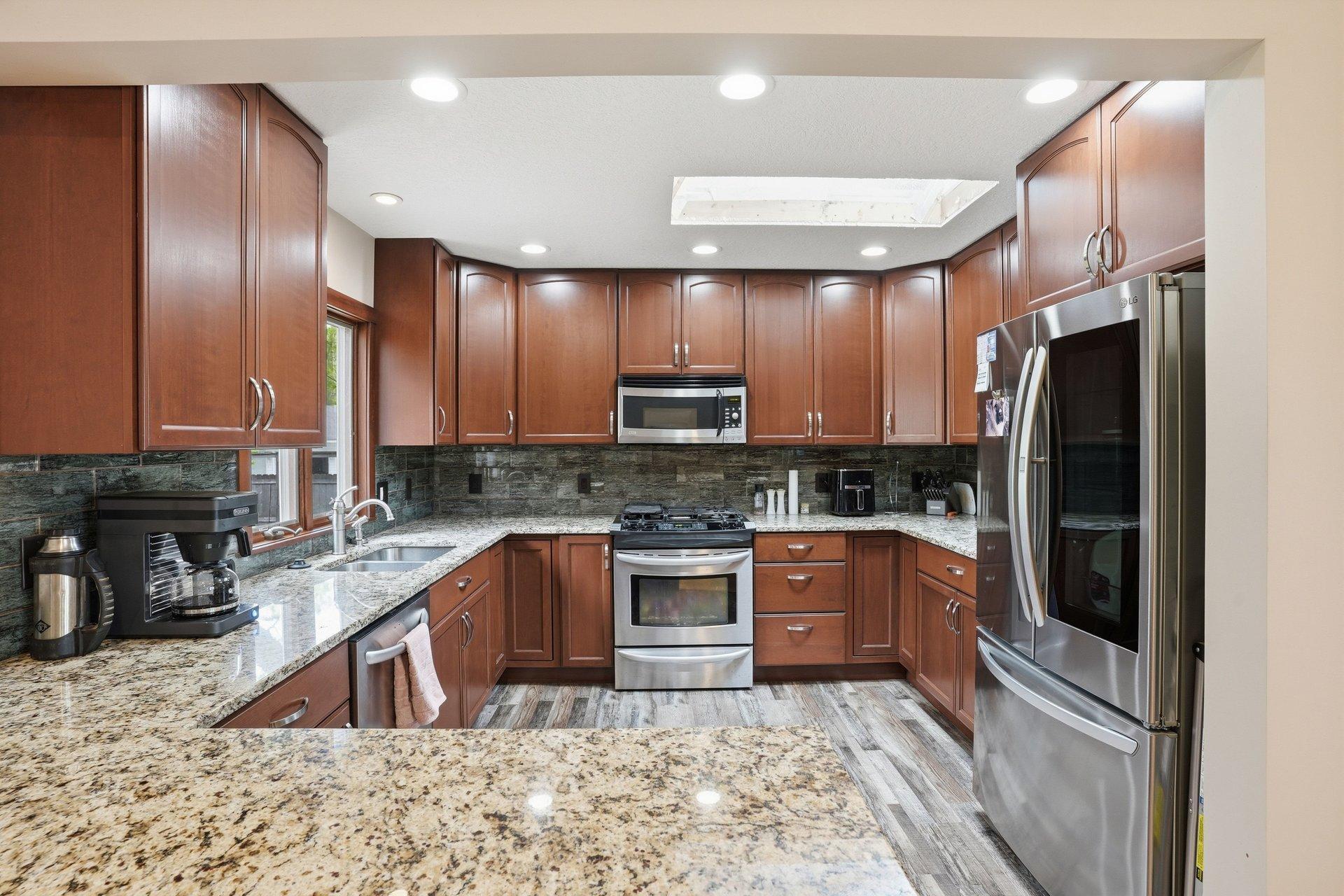 Beautifully updated kitchen featuring rich dark cabinetry, granite countertops, stainless steel appliances, and timeless finishes that blend style and functionality perfectly.
