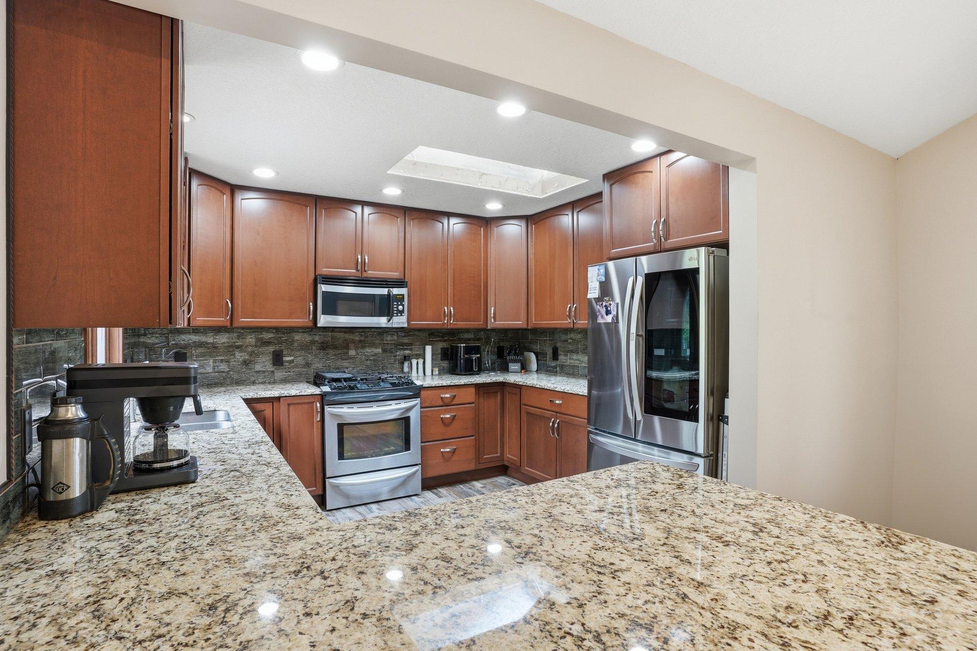 Beautifully updated kitchen featuring rich dark cabinetry, granite countertops, stainless steel appliances, and timeless finishes that blend style and functionality perfectly.