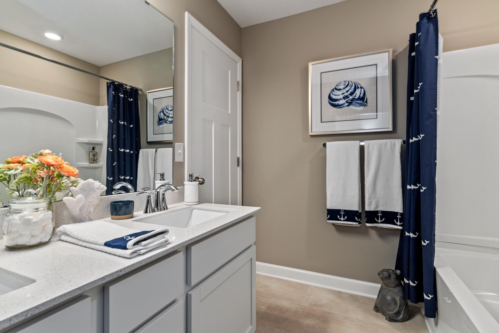 (Photo of decorated model, actual home's finishes will vary) Featuring a double vanity, this secondary bath is sure to keep everyone moving during those busy mornings!