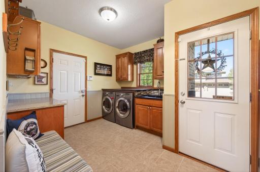 This multi-purpose entry and mudroom combines functionality and organization with built-in storage, laundry, shoe and coat racks, plus extra space for appliances and a refrigerator, serving as both a practical family entry and efficient workspace.