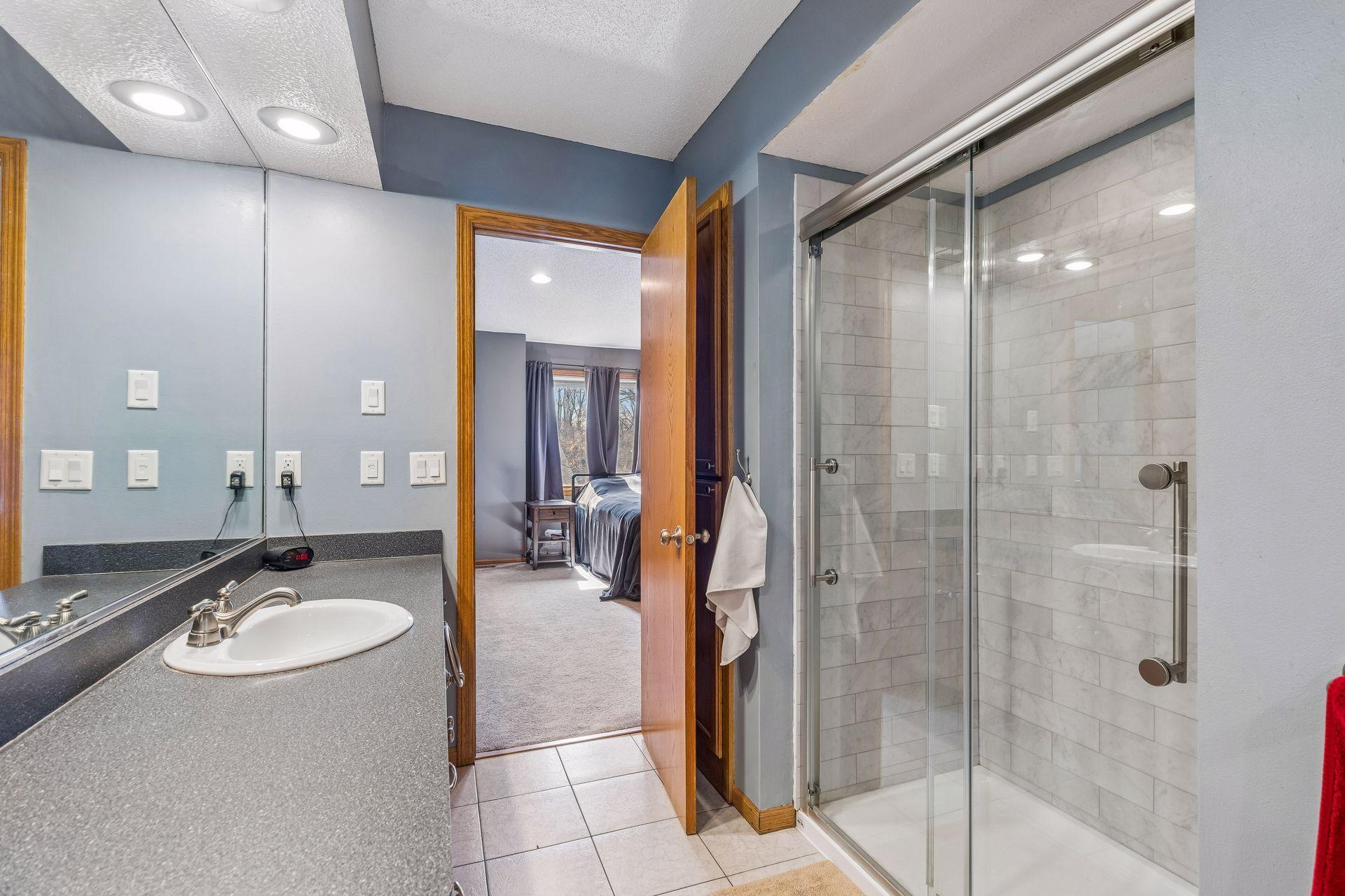 Another angle of the primary bath showcasing the shower (updated 2023) and ample counter space.