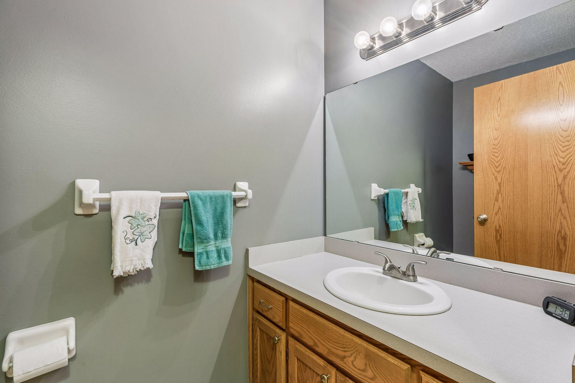 Main level 1/2 bath offers added convenience, complete with easy care linoleum flooring, a vanity, and bright wall lighting.