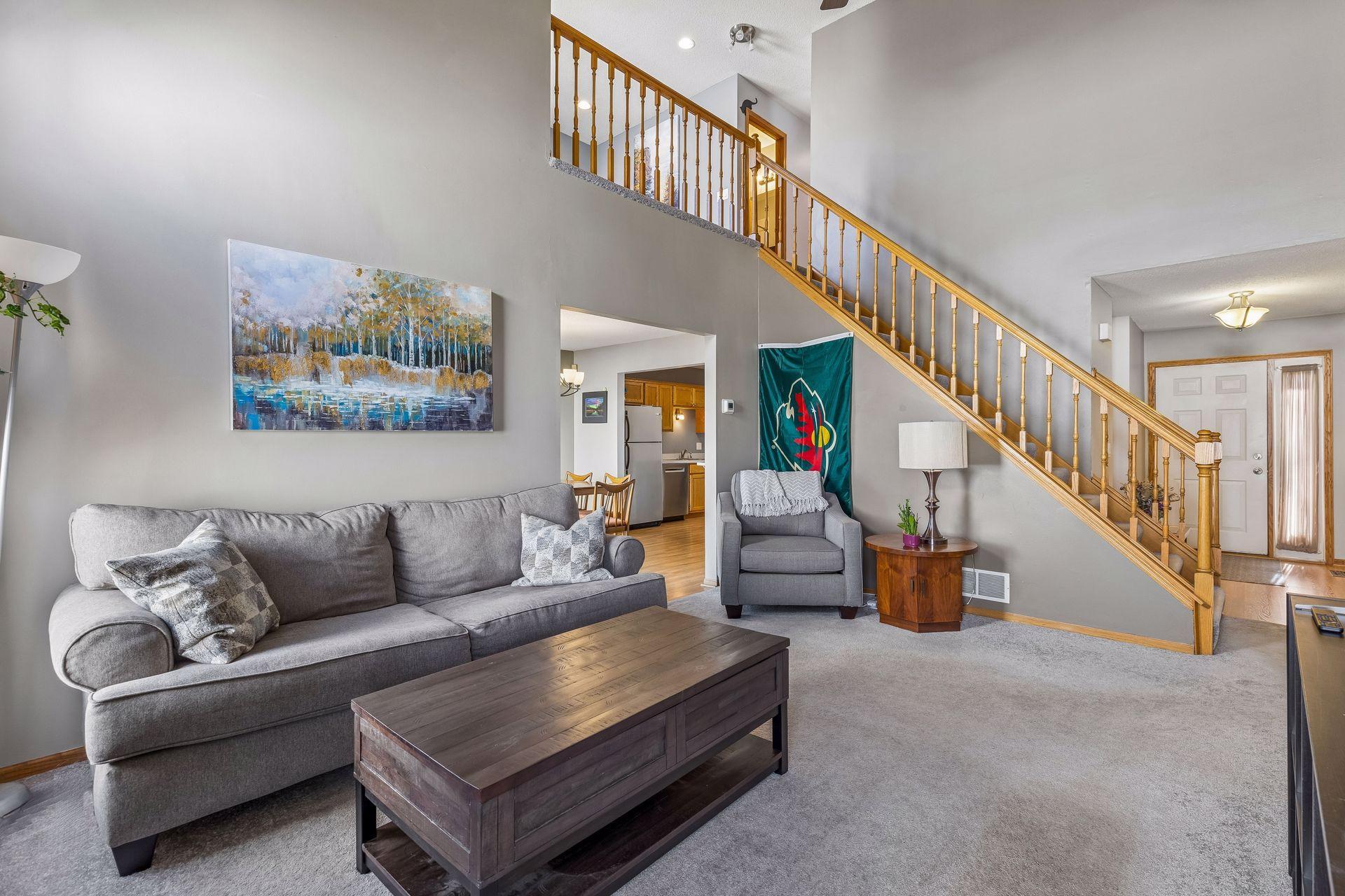From this angle, the living room feels beautifully connected, offering easy flow to the dining room, kitchen, a welcoming front entry, and an open staircase with balcony overlook.
