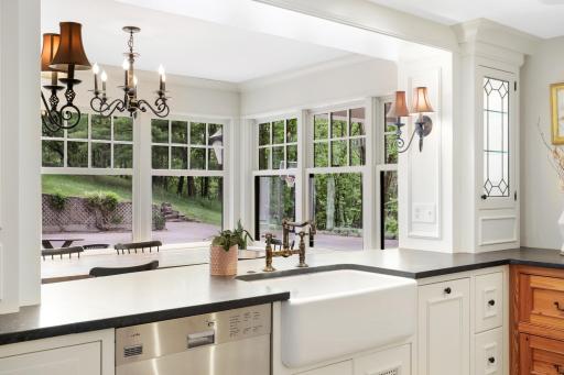The kitchen, dining, and living rooms are one bright, open, interactive space with heated, natural stone floors, walls of windows, and a gas fireplace.