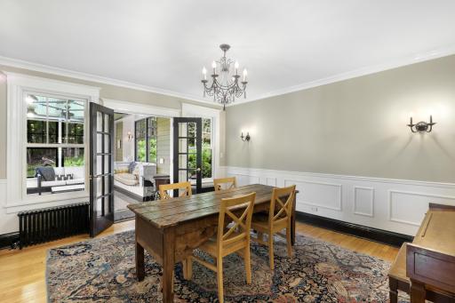 Glass French doors separate the sunroom and the formal dining room.