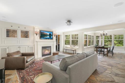 The kitchen, dining, and living rooms are one bright, open, interactive space with heated, natural stone floors, walls of windows, and a gas fireplace.