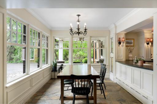 The kitchen, dining, and living rooms are one bright, open, interactive space with heated, natural stone floors, walls of windows, and a gas fireplace.