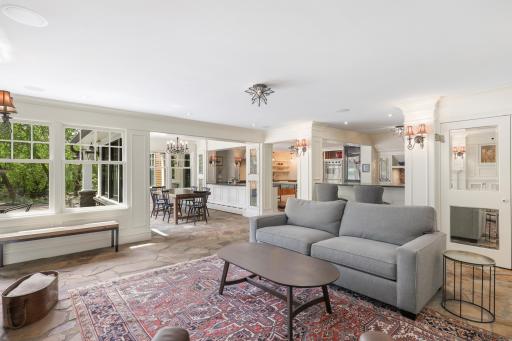 The kitchen, dining, and living rooms are one bright, open, interactive space with heated, natural stone floors, walls of windows, and a gas fireplace.