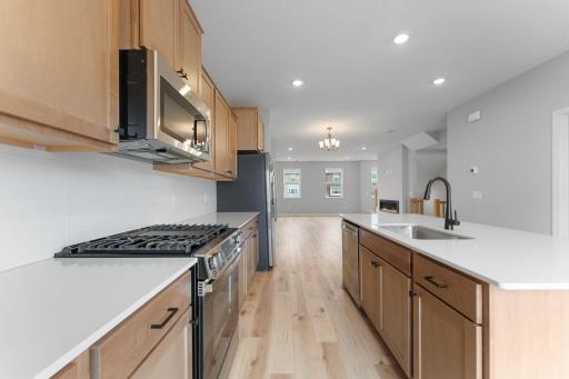 It's all in the details...matte black fixtures, quartz countertops, tile backsplash & stainless appliances. Notice the amount of surface space & cabinets! The 6' island provides add'l seating for causal dining. Similar home shown, options can vary.