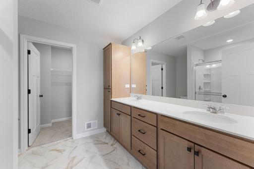 Owner's bath with dual vanity and large linen closet leading to 1 of 2 walk-in closets. Similar home shown, options can vary.