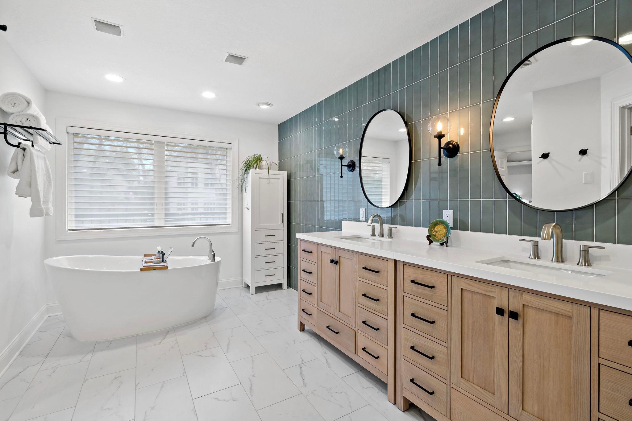 Remodeled primary bathroom with soaking tub, beautiful tile flooring, double vanity, and luxury shower.