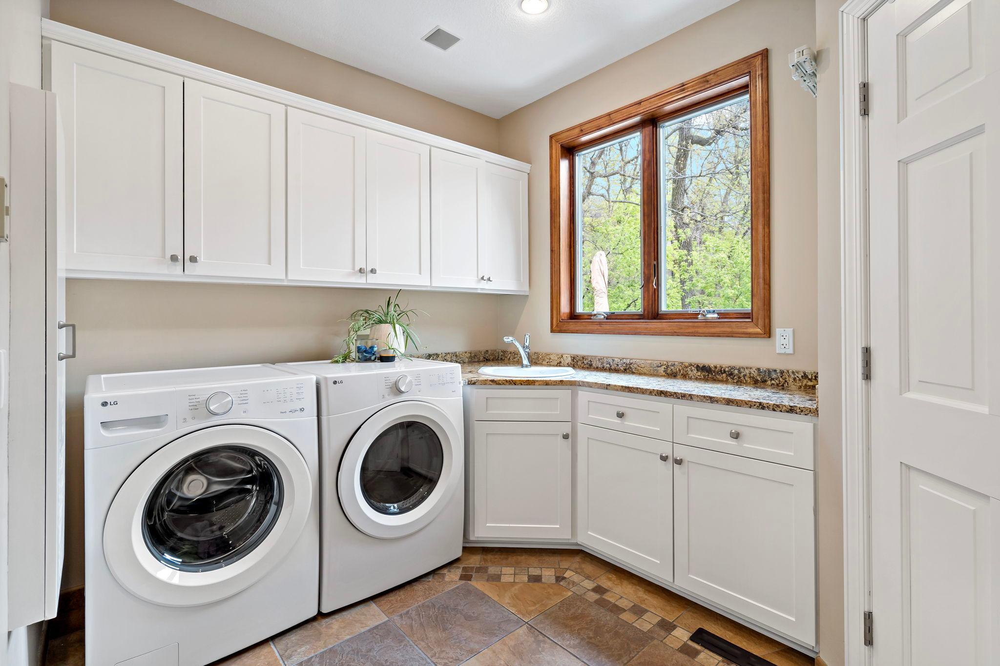 Very large laundry room with brand new LG washer and dryer, an abundance of cabinet and counter-space and tile floors