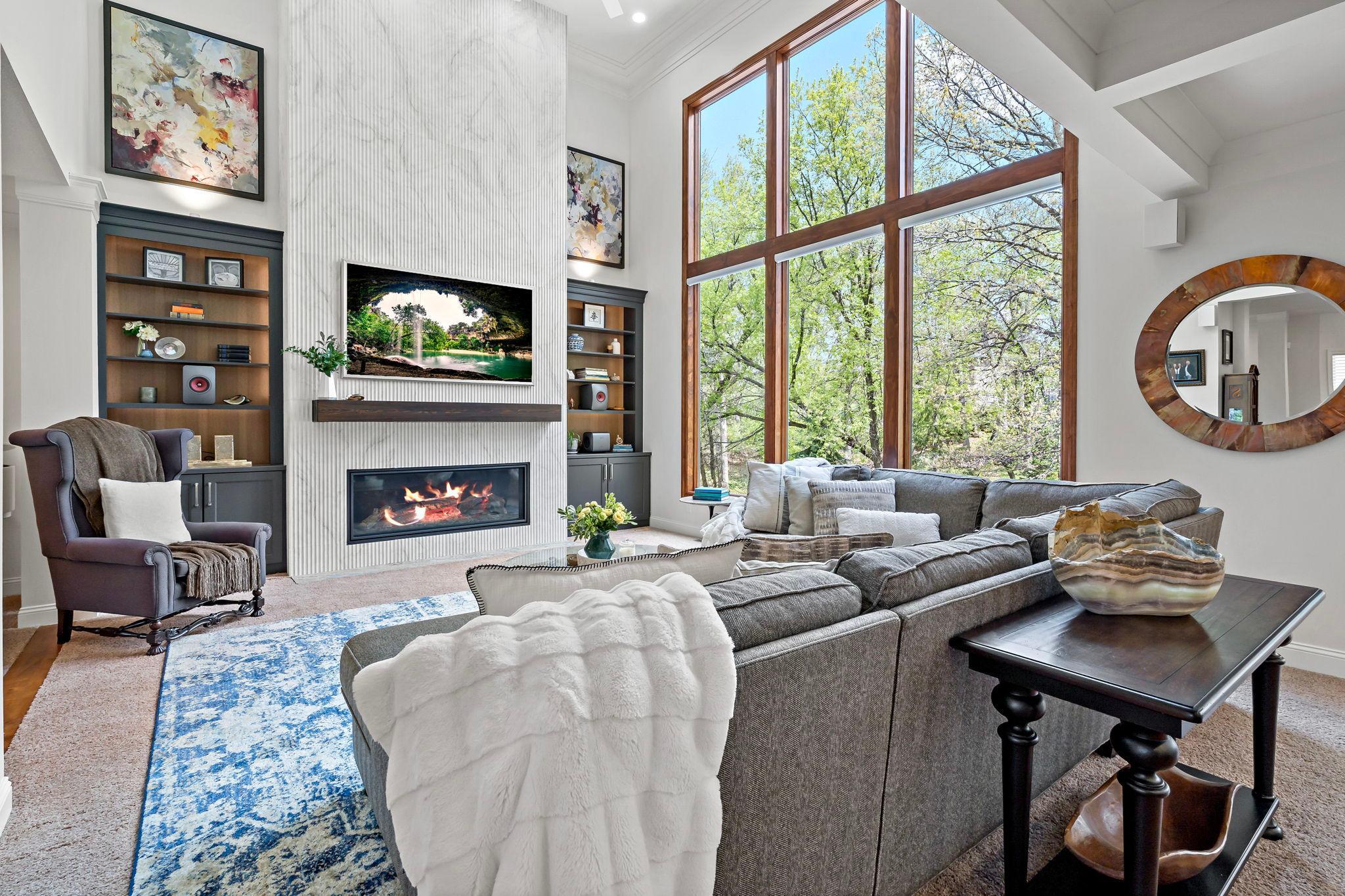 Incredible recently remodeled living room with dramatic floor to ceiling Brazilian tile fireplace, gorgeous built-ins and stunning panoramic windows