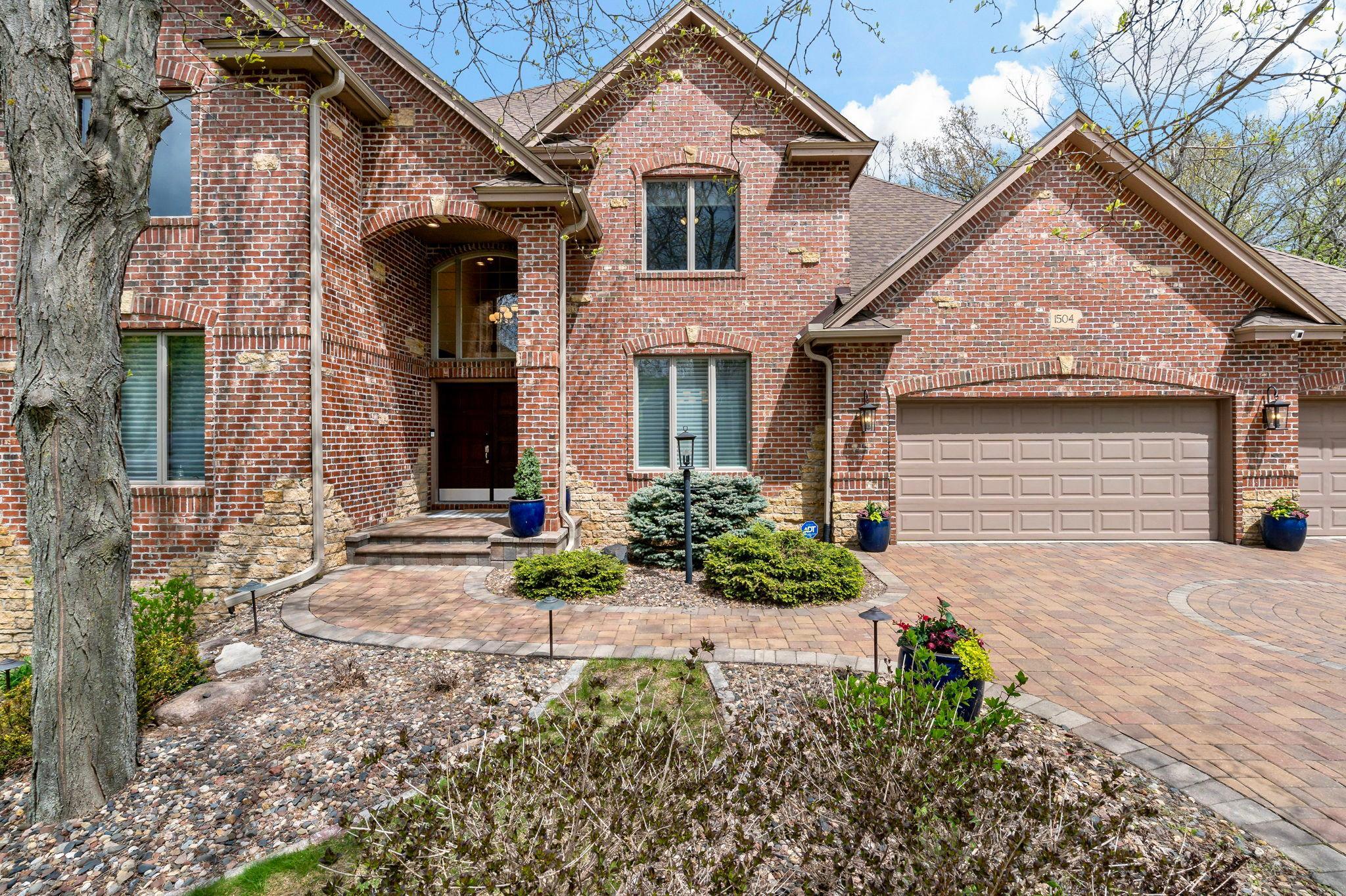 Exceptional curb appeal and timeless elegance in this stately executive home with brick exterior and impressive architectural detail, a grand entryway, professional landscaping, and an expansive paver driveway.