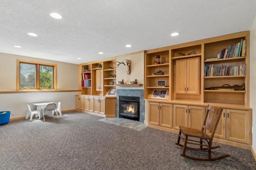Lower level amusement room with wall of built-ins and gas fireplace.