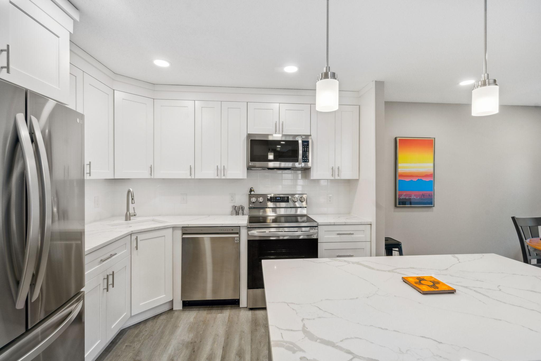 Bright and airy kitchen featuring a large breakfast bar, modern tile backsplash, and ample storage."