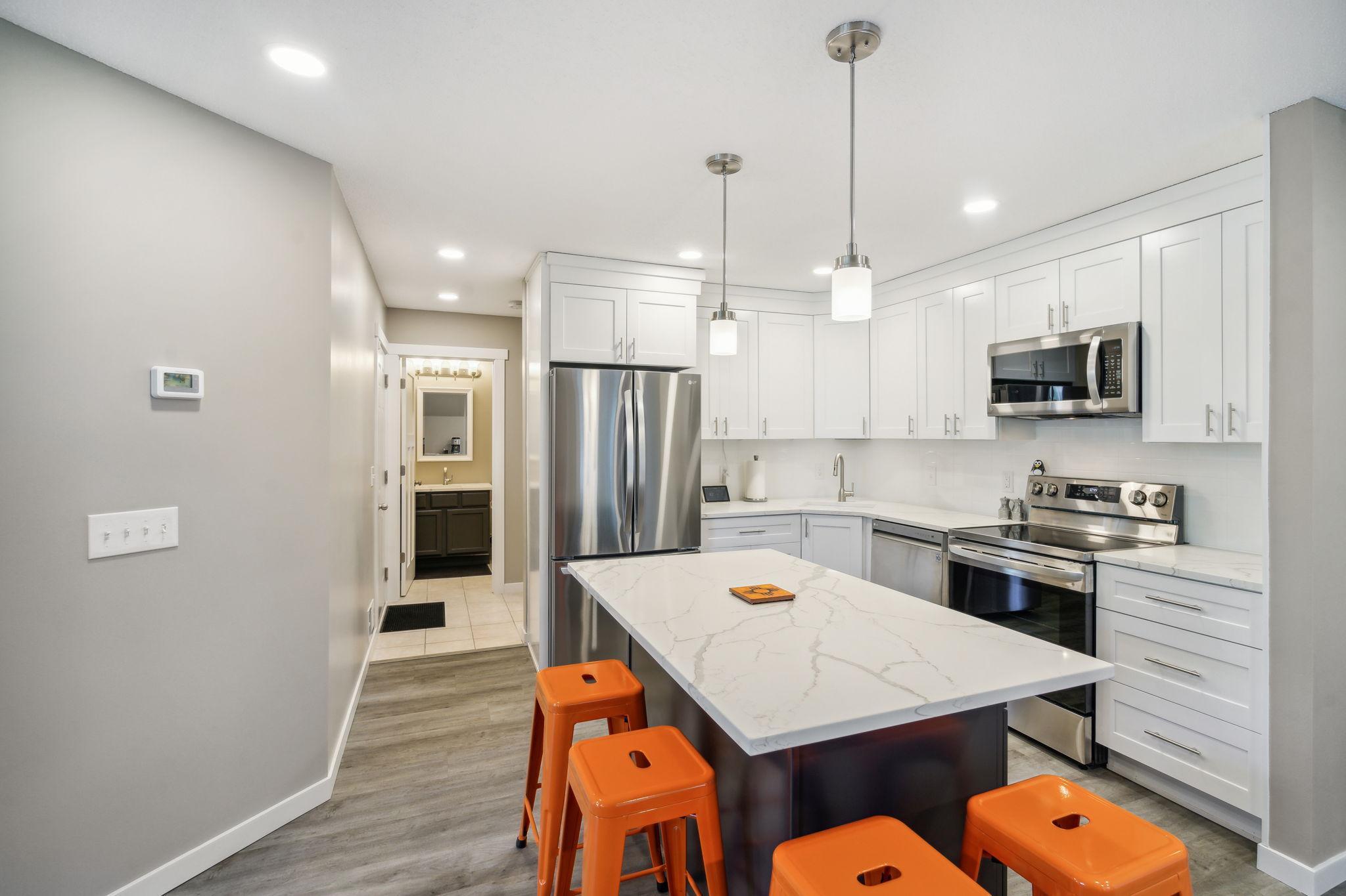 Bright and airy kitchen featuring a large breakfast bar, modern tile backsplash, and ample storage.