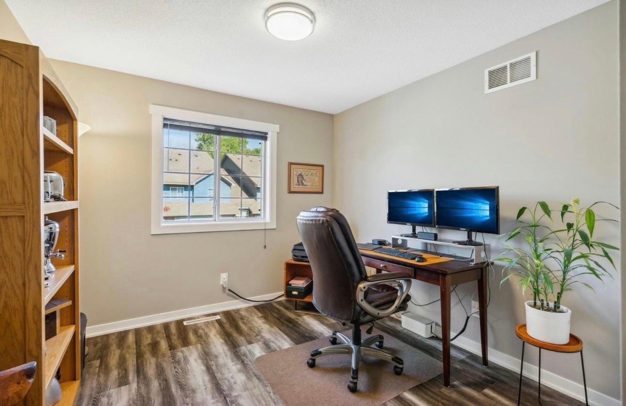 Bright and airy bedroom currently styled as a professional home office. Large windows provide plenty of natural light, while the durable flooring and neutral tones offer a clean, modern aesthetic.