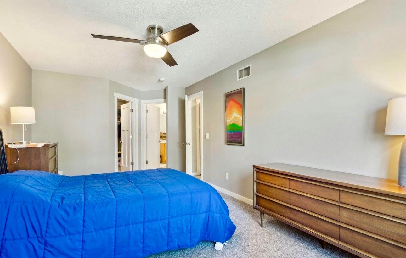 Expansive primary bedroom featuring a generous walk-in closet. The clean lines, neutral tones, and modern ceiling fan create a serene and comfortable retreat.
