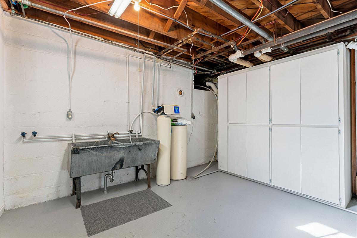 A clean, dry, freshly painted basement. This area has laundry hookups and a double sink.