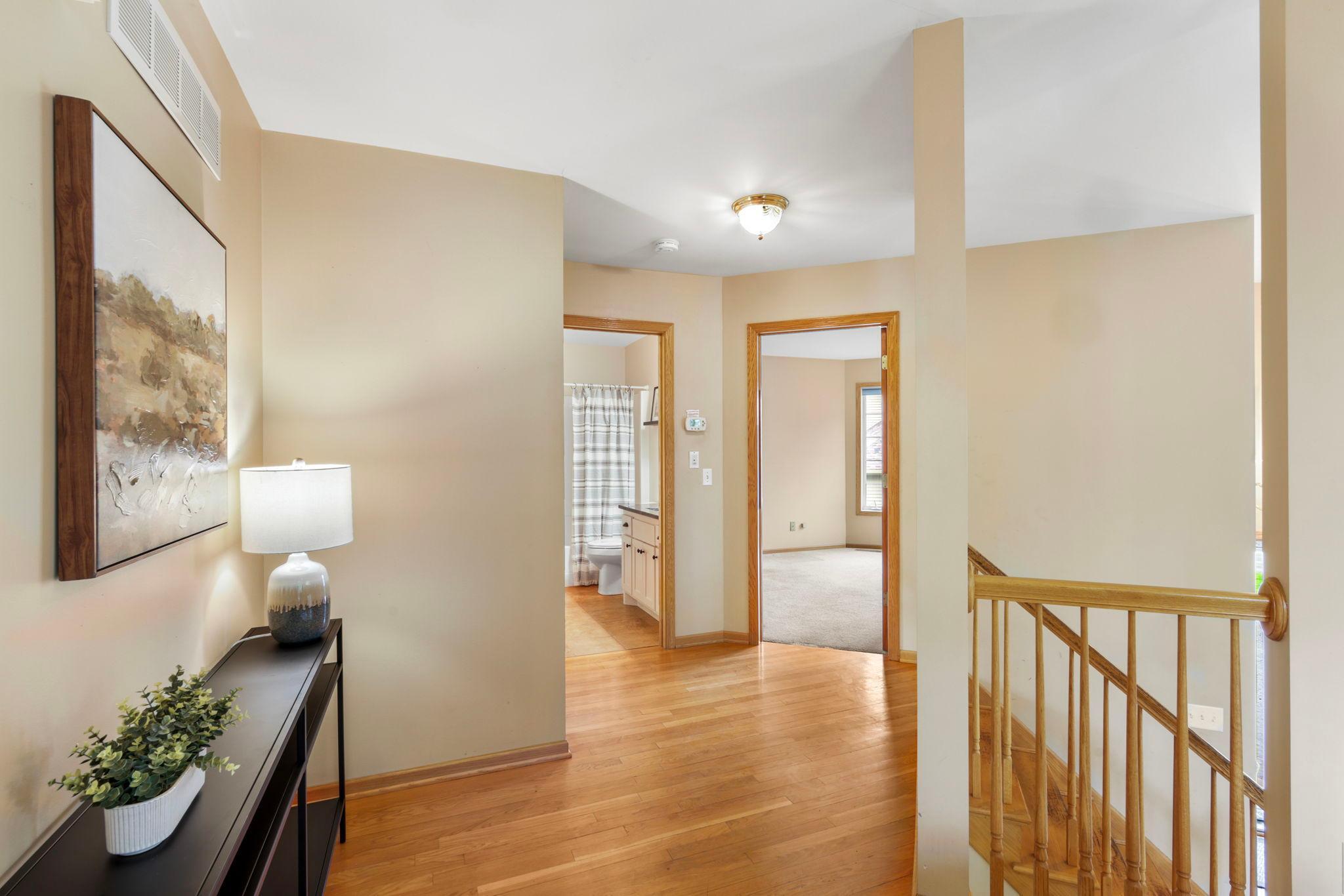 Upper level hallway leading to two upper level bedrooms and bath