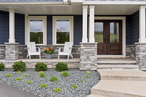 Inviting covered front porch with stone accents and welcoming double-door entry. Enjoy a peaceful country-living feel while still being conveniently located in the city. Perfect combination of privacy, luxury and modern comfort.