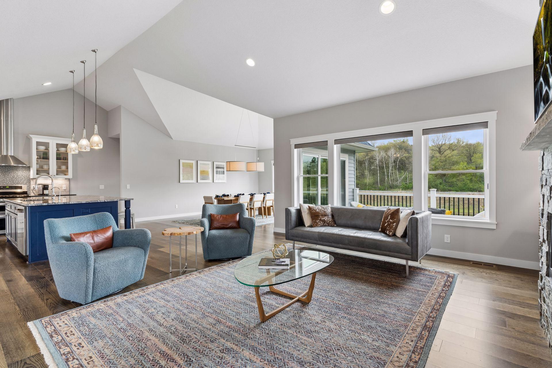 Sun-filled living room with large windows overlooking the private backyard and pond. Open floor plan with vaulted ceilings creates a spacious and airy feel throughout the home.