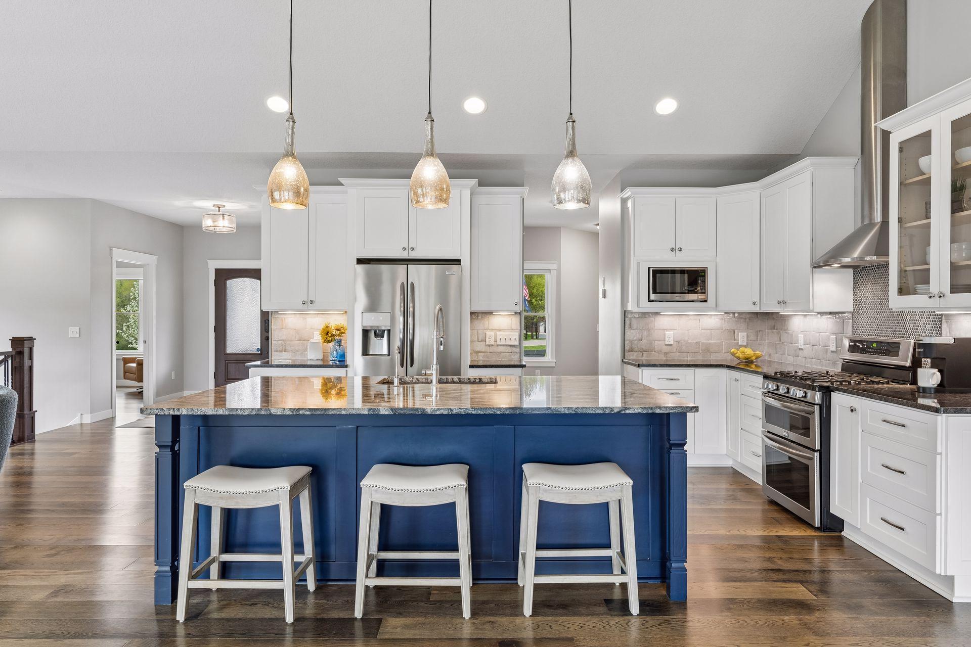 Chefs kitchen featuring a large island with seating, custom white cabinetry, stainless steel appliances, and upscale finishes. Open layout ideal for hosting gatherings and family living.