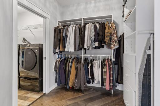 Spacious walk-in closet with custom storage system, built-in shelving, and direct access to the laundry room. Functional primary suite design with organized luxury living.