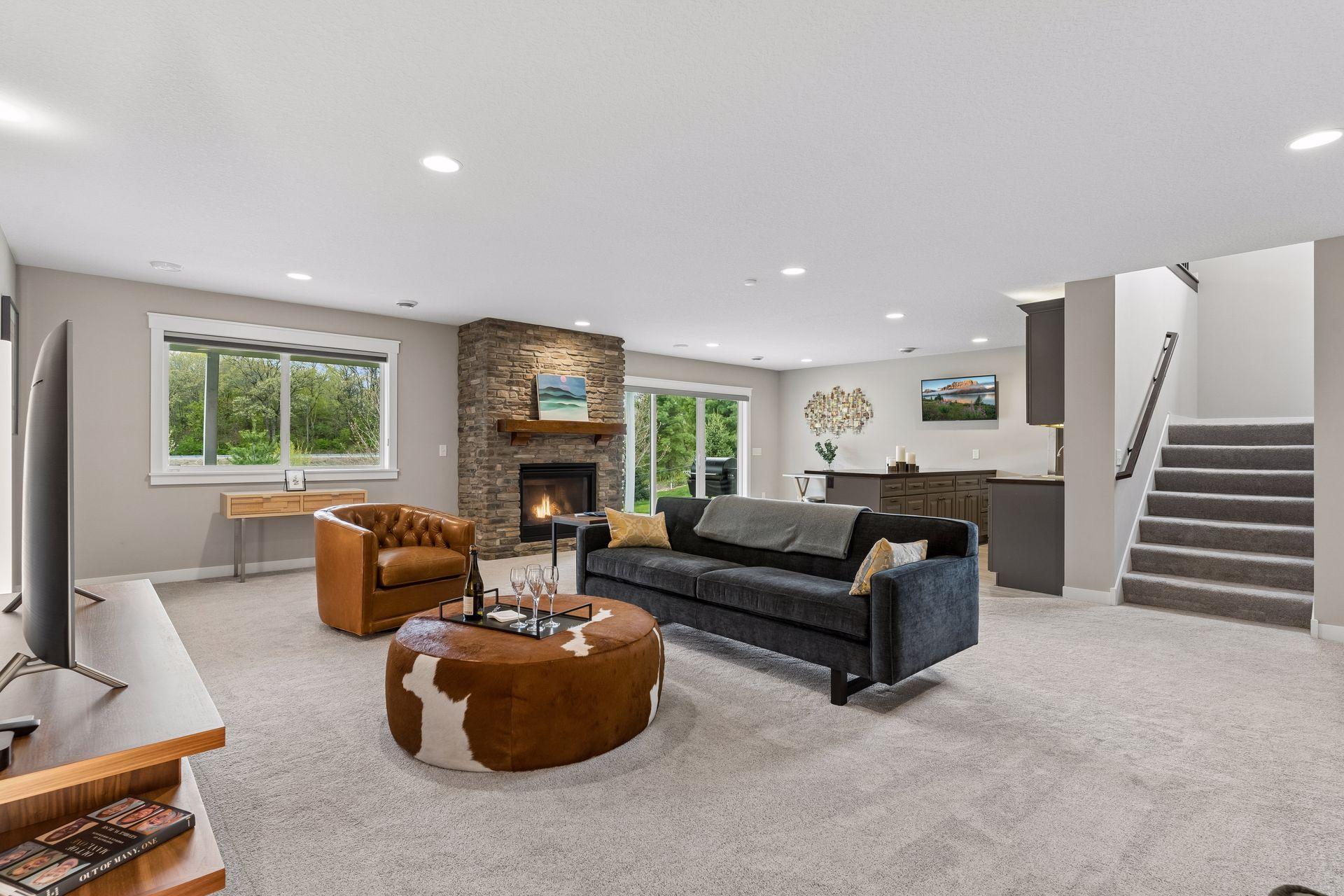 Expansive lower-level family room with stone gas fireplace, large windows, recessed lighting, and open-concept design. Perfect for entertaining, movie nights, or guest gatherings.