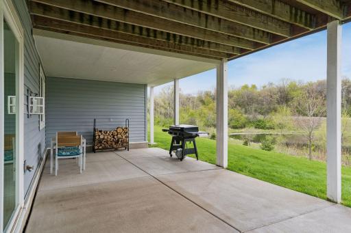 Covered walkout patio overlooking the private backyard and pond. Enjoy peaceful outdoor living, grilling, entertaining, and scenic nature views in every season.