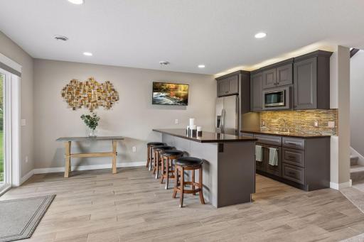Spacious lower-level wet bar and entertainment area with custom cabinets, tile flooring, and walkout access to the covered patio. Great for hosting family and friends.