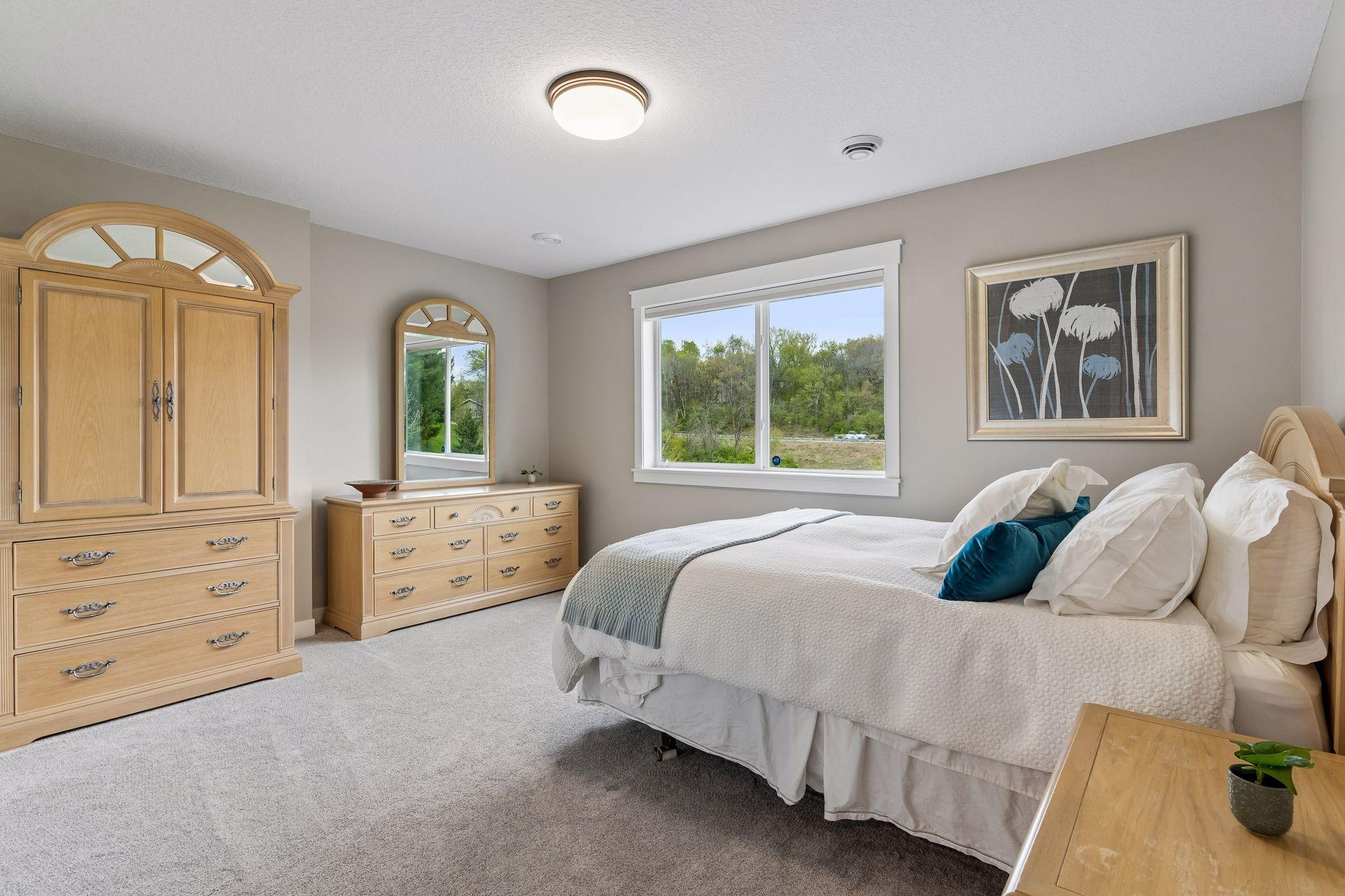 Bright lower-level 2nd bedroom with large window, soft carpeting and spacious layout. Comfortable guest bedroom with peaceful nature views and generous storage space.